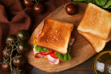 Tasty sandwiches with bacon and tomatoes on wooden table, flat lay