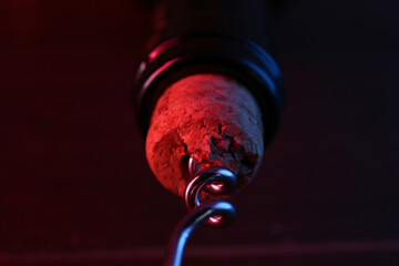 Wine bottle with corkscrew in lights on table, closeup