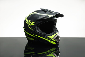 Modern motorcycle helmet with visor on mirror surface against light grey background