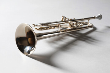Obraz premium Shiny trumpet on light grey background, space for text. Wind musical instrument