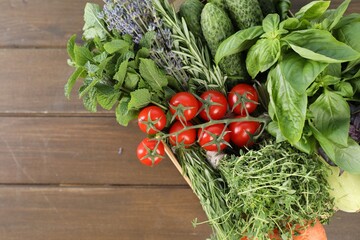 Different aromatic herbs and vegetables in crate on wooden table, top view. Space for text