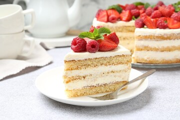 Tasty sponge cake with fresh berries and mint served on light gray table, closeup
