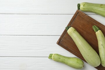 Raw green zucchinis on white wooden table, top view. Space for text