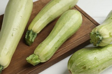 Raw green zucchinis on white wooden table, closeup