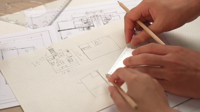 Professional engineer team discussion about house design on meeting table with architectural equipment and building blueprint scatter around at modern office. Focus on hand. Closeup. Delineation.