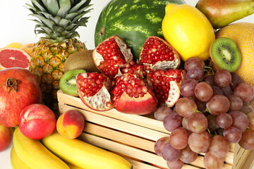 Wooden crate with many different fresh fruits on white background