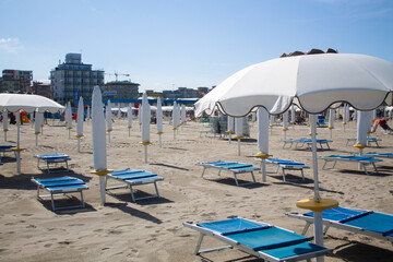 Beach chairs and umbrellas. Sun loungers on a beach in Italy on a bright sunny day by the sea