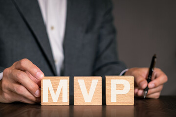 There is wood cube with the word MVP. It is an abbreviation for Minimum Viable Product as...
