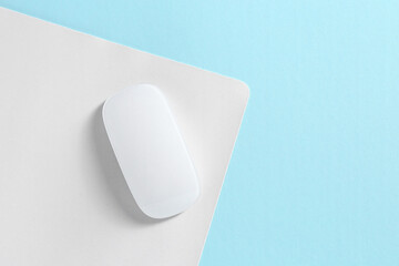 Wireless mouse and mousepad on light blue background, top view. Space for text