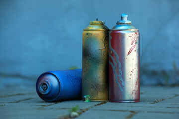 Many spray paint cans on pavement outdoors