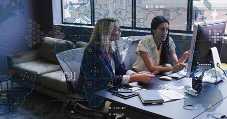 World map and data analytics image over businesswomen working in modern office