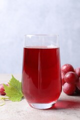Ripe grapes and tasty juice on grey table