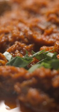 Brushetta tomato preparation rotating with basilic pouring slow motion, vertical view