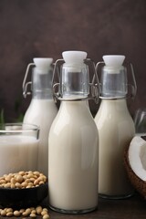 Different types of vegan milk and ingredients on wooden table