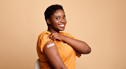 Successful Coronavirus Vaccination. Black Woman Showing Vaccinated Arm After Covid-19 Vaccine Injection Shot Posing Smiling To Camera On Beige Background. Corona Virus Immunization Concept. Panorama
