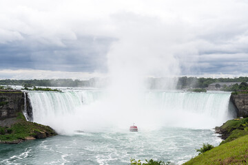 A tour boat cruises towards to mist at the base of the Horseshoe Falls in Niagara Falls Ontario.