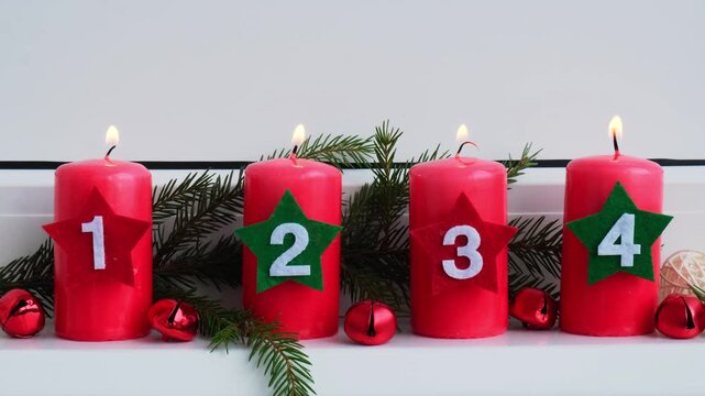 Traditional four advent weeks before Christmas holidays. Red candles with numbers burning and plastic free decoration fir brunches in windowsill. Winter cozy home time