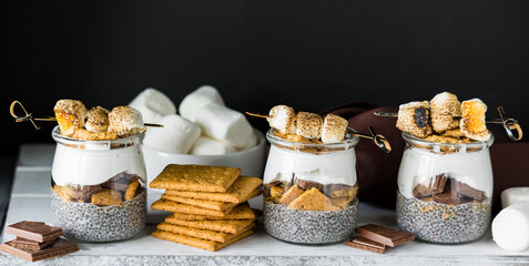 Naklejka premium Homemade smores chia puddings in a line surrounded by ingredients.