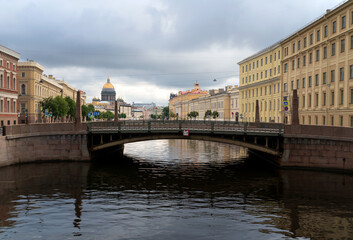 Naklejka premium View of St. Isaac's Cathedral and the Moika River embankment against the background of the Kissing Bridge on a summer morning, St. Petersburg, Russia