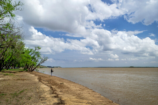 
Beautiful postcard of the banks of the Parana River, where we see a man fishing, a large cloudy and blue sky, we also see great green vegetation and beautiful parks in the province of Entre Rios Arg.