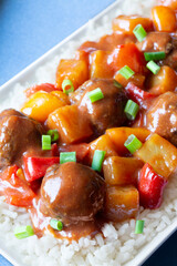 Close-up of Sweet and Sour Meatballs with Pineapple, Peppers, Green Onion Scallions and Rice