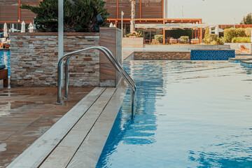 Luxurious swimming pool with stainless steel ladder and modern poolside area