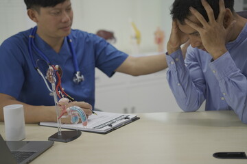 A male doctor in a hospital consults with a patient, using medical equipment and a computer....