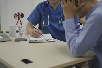 A male doctor in a hospital consults with a patient, using medical equipment and a computer....