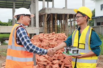 A male engineer, wearing a hardhat and helmet, examines blueprints on a construction site. Working...