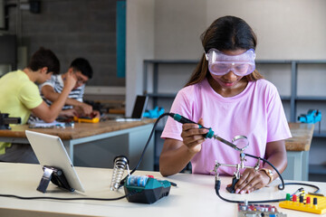 Teen African American female high school student in electronics class working on a project alone....