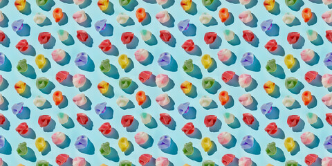 A pattern of colorful cotton candy pieces arranged in an orderly fashion on the pastel blue background, with shadows cast sunlight