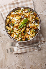 Fusilli pasta with fried eggplant, garlic and feta cheese close-up in a bowl on the table. Vertical top view from above