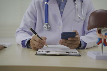 A doctor sits at a desk in a medical clinic, by tools like a stethoscope and prescription...