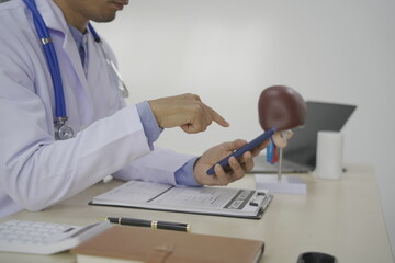 A doctor sits at a desk in a medical clinic, by tools like a stethoscope and prescription...