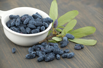 White bowl filled with Honeyberry haskap berries on wooden table