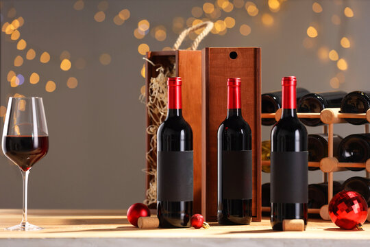 Bottles of wine, glass, wooden gift boxes, barrel corks and red Christmas balls on table