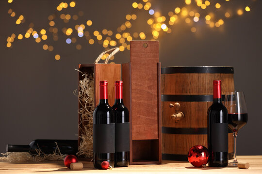 Bottles of wine, glass, wooden gift boxes, barrel corks and red Christmas balls on table