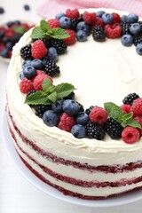 Tasty sponge cake with different berries and mint on white table, closeup
