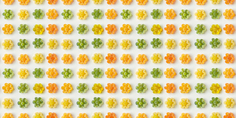 Analogous green, yellow, orange flower-shaped gummy candies background, flat lay photography, top view, simple white background, high resolution, no blur effect, no shadows, natural lighting