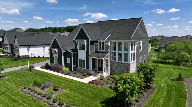 Modern Single family home with neat green garden in american suburb neighborhood. Sunny day in summer season. Aerial approaching shot.