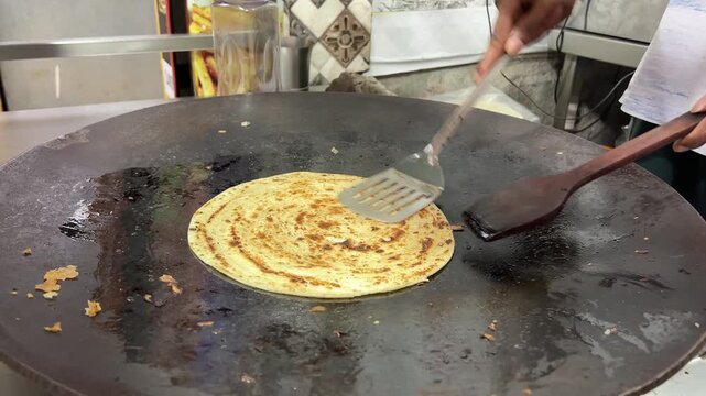Close up shot of a man preparing lacha paratha at a shop in India
