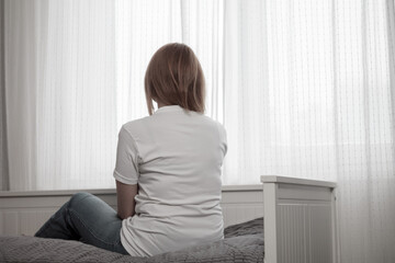 Depressed woman: sitting, hugging her knees, head down, face hidden by hair, expression of despair...