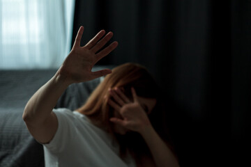 The woman in the photo looks depressed and scared, she has suffered from domestic violence or emotional abuse. Her posture is hunched, and her facial expression is anxious and sad