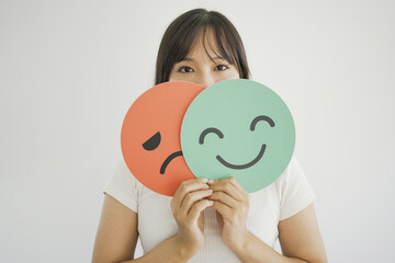 Woman hands holding sad face hiding behind happy face, bipolar and depression, mental health, split...