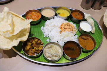 A South Indian thali or meal consists of steamed rice, sambar, rasam, vegetable curries, Avial, coconut chutney, pickles, papadum, curd or yogurt, and a sweet dish kheer. Ghee Podi masala.Sadya meal.