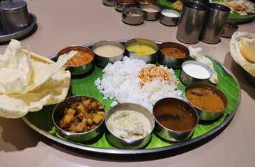 A South Indian thali or meal consists of steamed rice, sambar, rasam, vegetable curries, Avial, coconut chutney, pickles, papadum, curd or yogurt, and a sweet dish kheer. Ghee Podi masala.Sadya meal.
