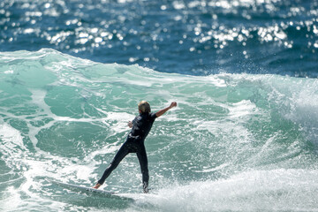 Caucasian male Australian surfer from behind surfing a wave