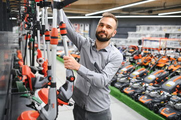 happy customer with electric lawn trimmer in hands at garden equipment store