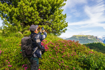 Middle-aged man with backpack taking photos of mountains on smartphone. Dolomites, Italy, South Tyrol. Travel, Active lifestyle after 50. High quality photo