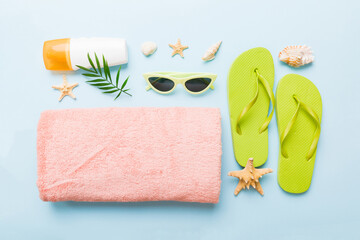 Summer holiday concept. Top view of beach towel, flip flop and sunscreen cream on table Top view...